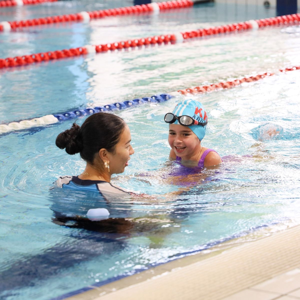 Instructor guiding a child through a swimming lesson in the KRB pool